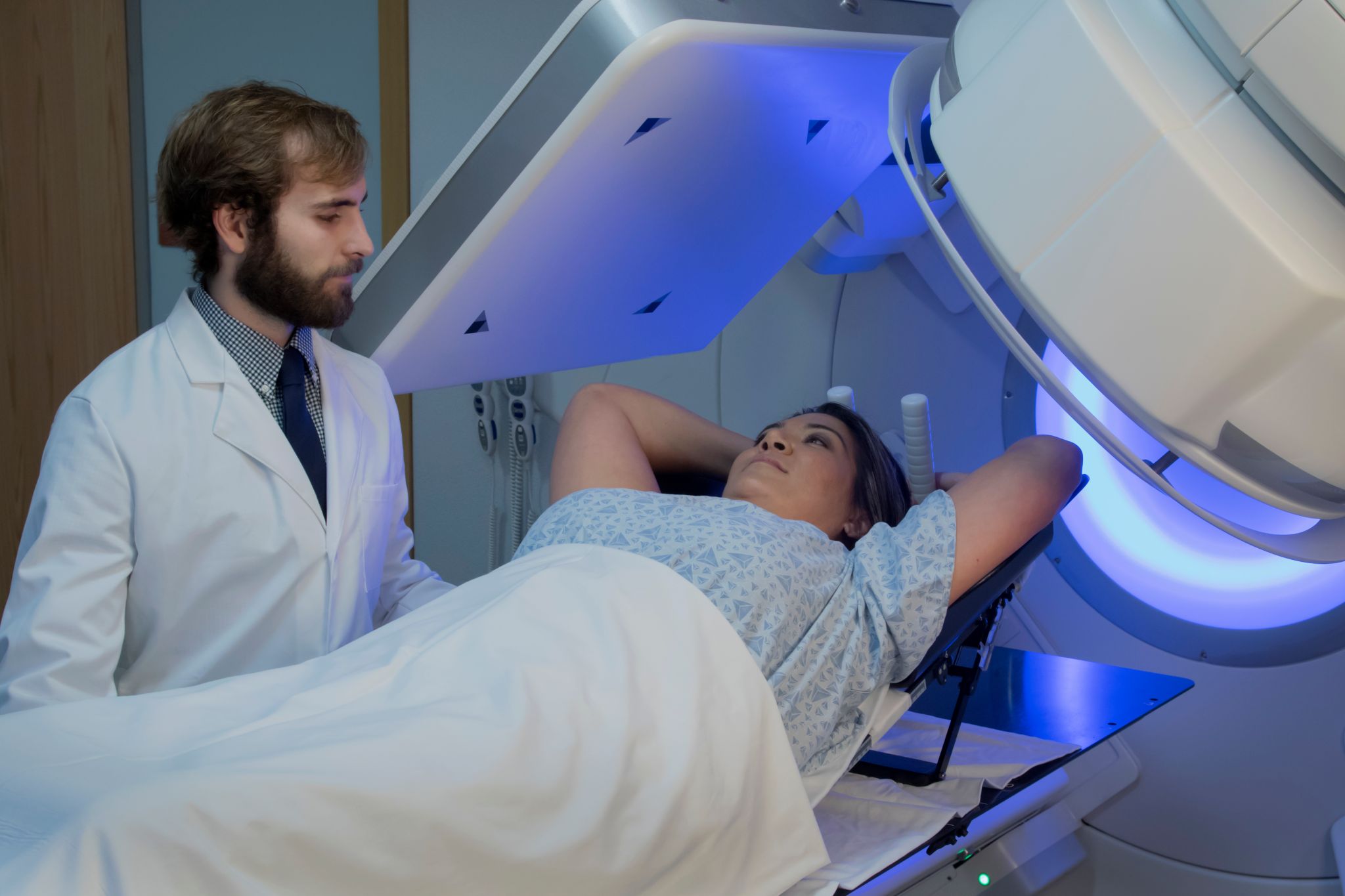 Photo d'une patiente souriante qui effectue une radiothérapie au côté d'un professionnel de santé. 