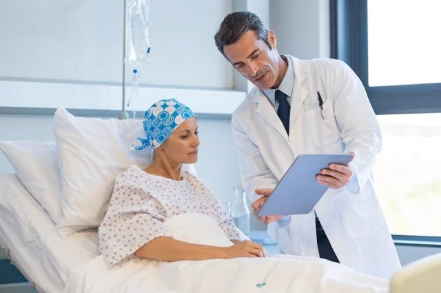 Photo d’un professionnel de santé présentant à sa patiente, sur son lit de soins, les résultats de son examen.