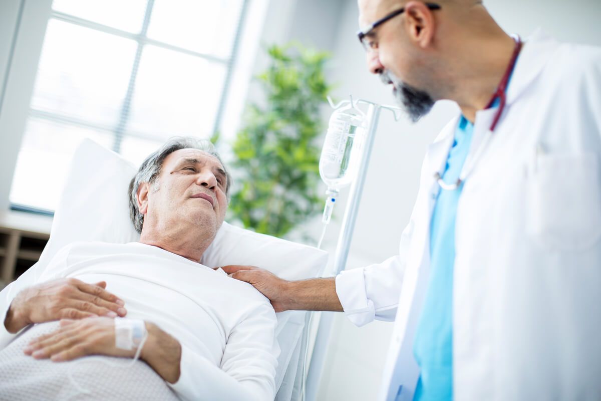 Photo d’un patient allongé sur son lit de soins, souriant à son médecin.