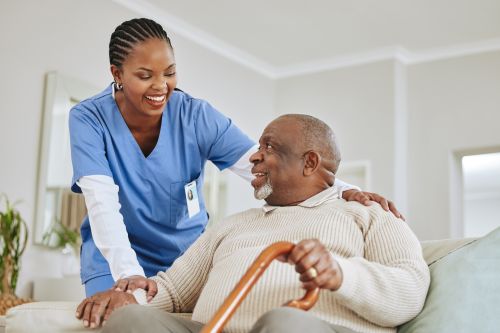 Photographie d'une infermière souriante tenant l'épaule et le poignet de son patient.